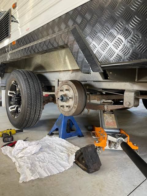 Caravan on a jack stand with the wheel off for a brake and bearing service