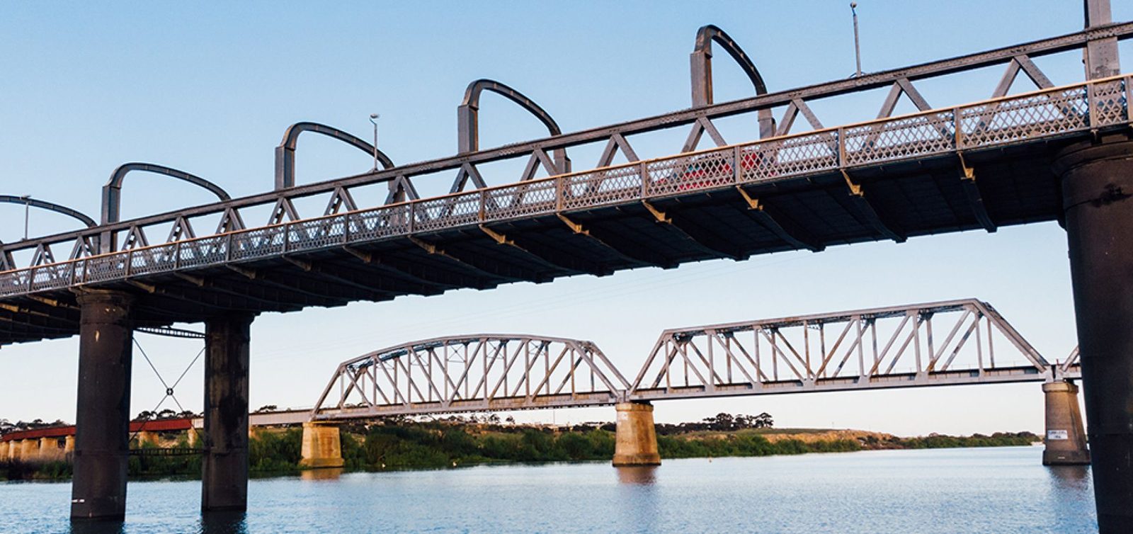The road and rail bridges over the Murray River at Murray Bridge, seen from the water at dusk