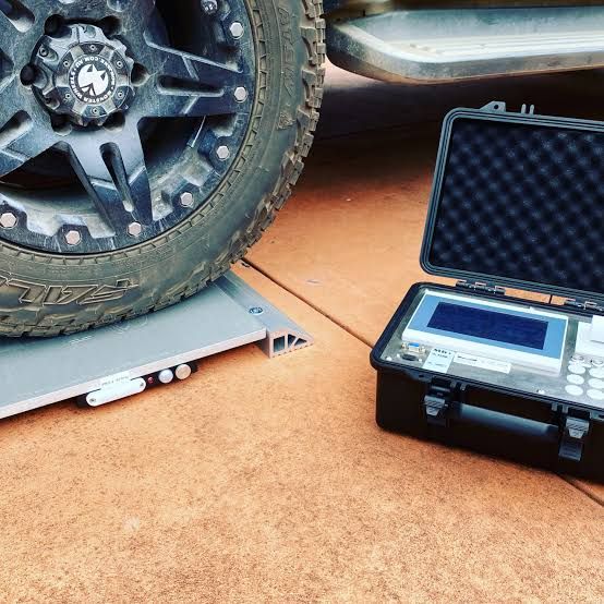 A tow vehicle wheel on a portable weigh pad next to the weighing case