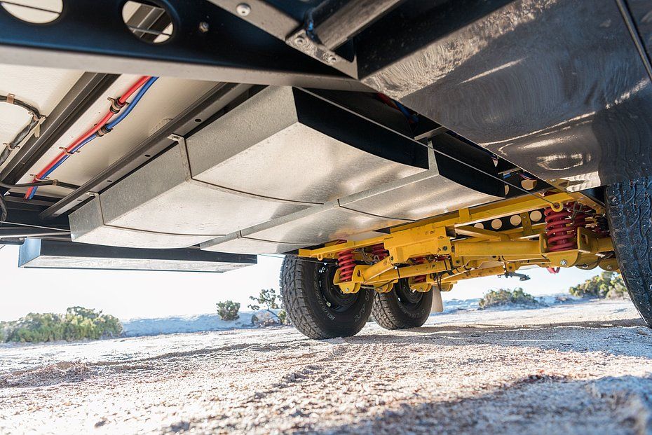 Underside of a tandem-axle caravan showing the suspension and alignment