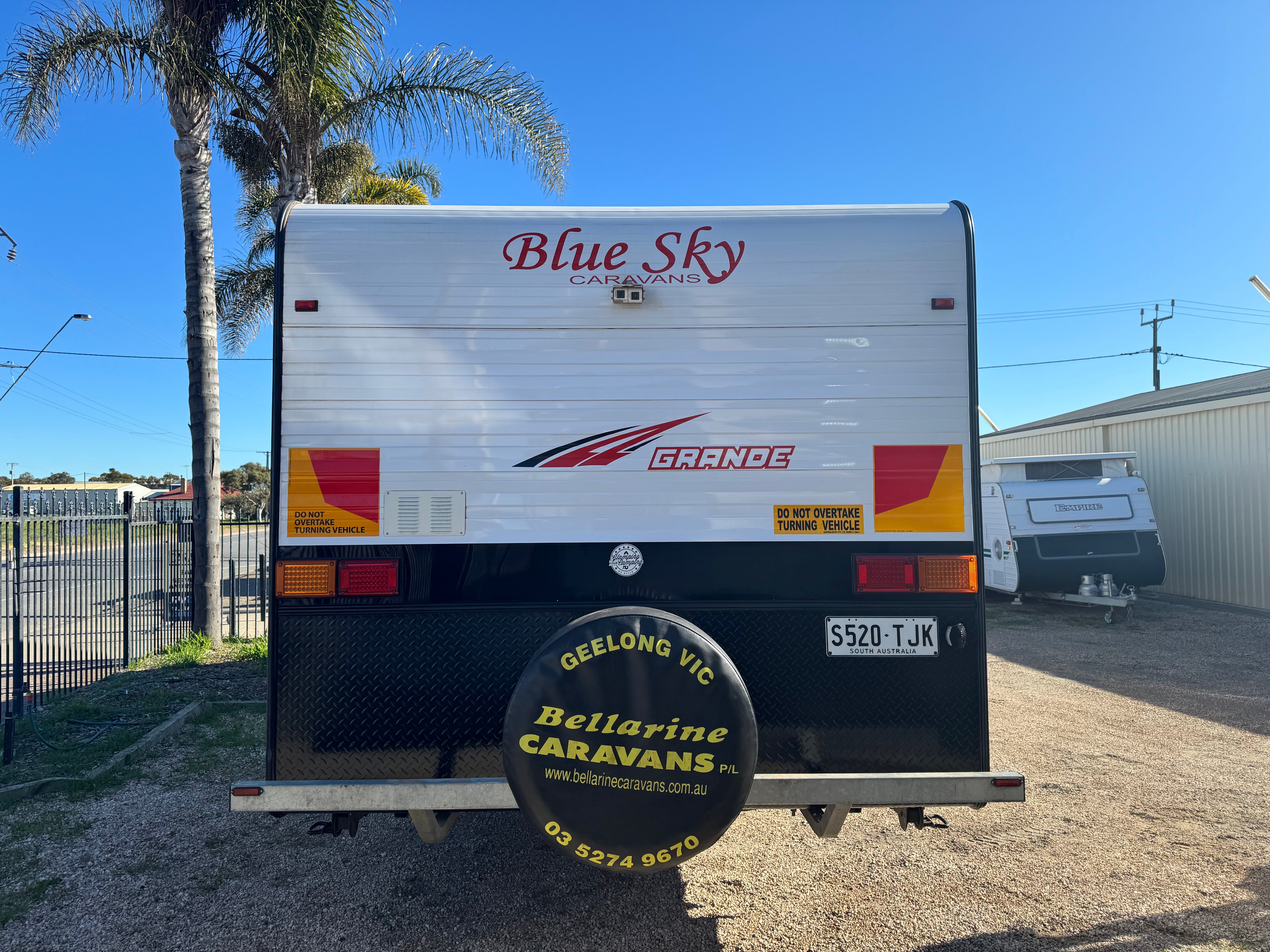 Back view of a caravan with 'Blue Sky Caravans' branding on a clear day.
